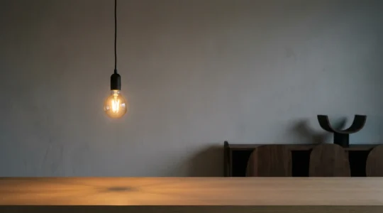 A dimmable LED bulb glowing softly at low brightness in a modern living room setting with warm ambient lighting